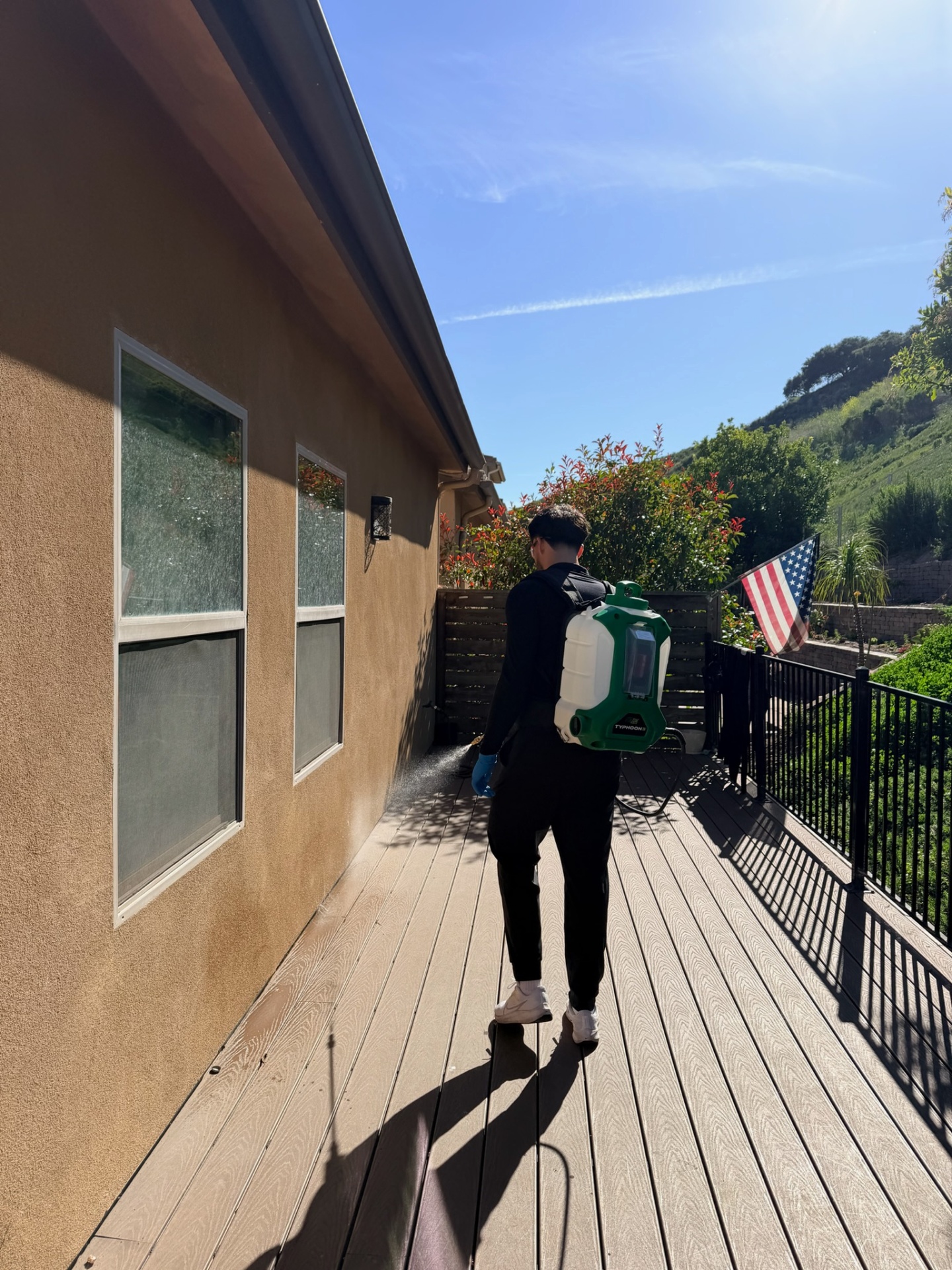 Eddie spraying natural Naturecide treatment around a home